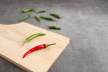 Pepper of thailand on the wooden cutting board placed on the black cement floor. High angle view.