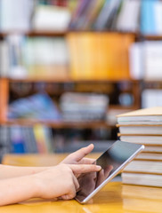 Closeup hands of a child use tablet computer in library. Empty space for text