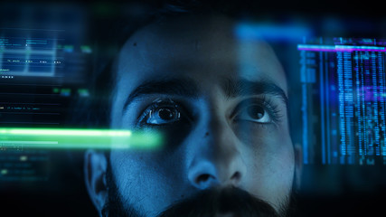 A close up of a young man eye controlling a futuristic computer system. Computer programmer coding on futuristic holographic display.