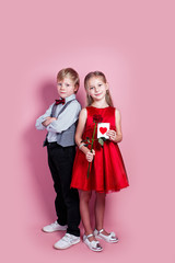 Wall Mural - cute six year old girl with a Valentine's card in her hand and funny boy on pink background