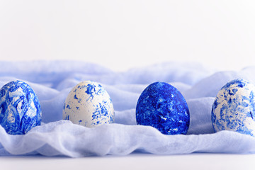 Easter eggs in row of white and classic blue on soft blue towel on white background