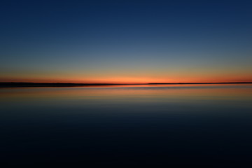 Wall Mural - Glowing twilight red colors on the horizon on a blue sky background at sunset