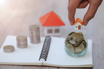 A woman holding a house on a pile of coins is planning savings money. concept for property ladder, mortgage and real estate investment. for saving or investment for a house.