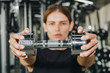 © Yuliia - sport, fitness, bodybuilding, weightlifting and people concept - close up of woman flexing arms with dumbbell in gym.
