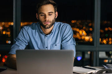 Wall Mural - Young businessman working late at night on a laptop