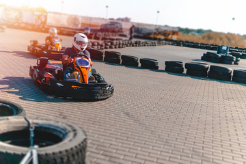 A driver in gear and helmet drives a racing car. In action. Go karts racing, sreet karting, rent. extreme sport. fun entertainment for drivers. Soft light glow, copy space