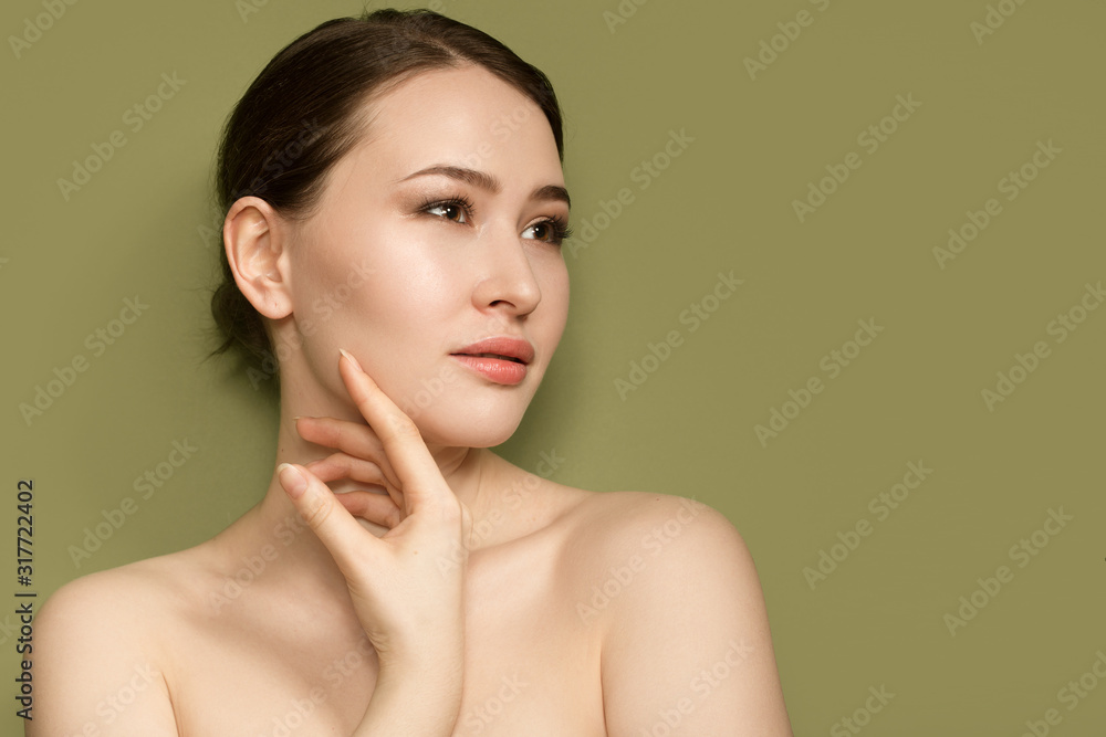 beautiful fashionable woman. Portrait with natural make-up on a green background. hand touches her face - obrazy, fototapety, plakaty 