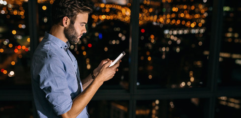 Wall Mural - Young businessman working late at night reading text messages