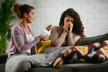 Woman broke up with boyfriend, she is crying and sister is trying to calm her down. Beautiful women sitting in living room.