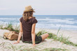 Young woman resting by the sea. Girl sitting on the beach. Enjoying life, summer lifestyle, relaxation and travel concept
