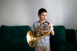 Caucasian boy learns to play horns, light window