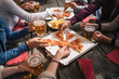 Group of young people having lunch on a terrace of an apartment at sunset - Millennials have fun together on a festive day eating pizza and drinking beer