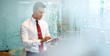 © marvent - Handsome young businessman wearing a white shirt and red tie working on a digital tablet while standing alone in a modern office