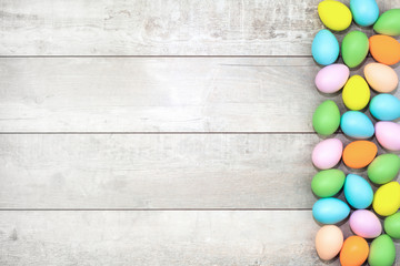 Wall Mural - Several bright color dyed easter eggs on wooden background in flat lay with copy space. Border for Happy Easter minimal concept card or banner