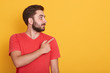 © sementsova321 - Horizontal shot of smiling young handnsome Caucasian man pointing to empty space aside with his index finger, wearing casual clothing, over yellow wall. Copy space for advertisment or promotion