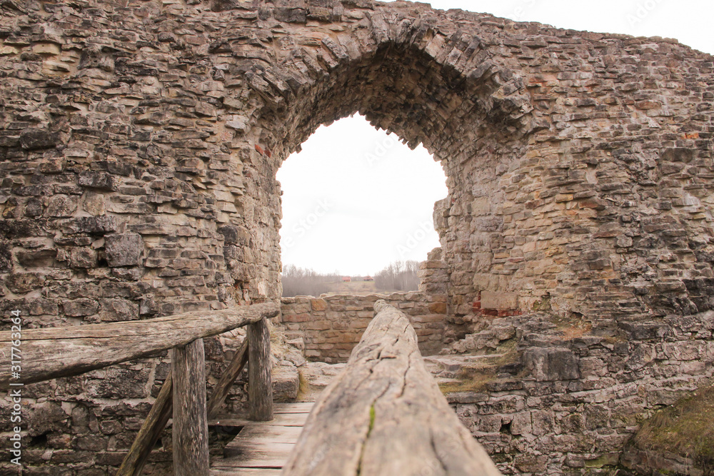 Portal in the medieval castle wall. The wall built of rocks and bricks ...