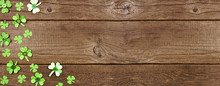 St Patricks Day Banner With Corner Border Of Handmade Paper Button Shamrocks. Top View Over A Rustic Wood Background With Copy Space.