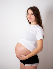 The young beautiful pregnant woman experiences strong emotions on a white background