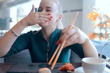 girl eats sushi and rolls in a restaurant / oriental cuisine, Japanese food, young model in a restaurant