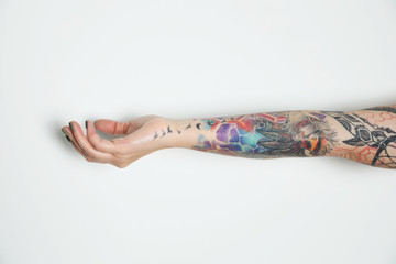 Woman with colorful tattoos on arm against white background, closeup