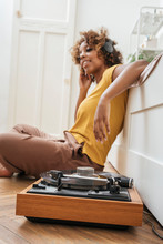 Young Woman Listening To Music With Headphones And Record Player At Home
