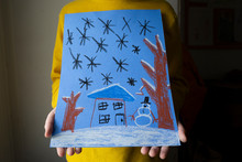 Close-up Of Child Holding Oil Pastel Drawing Of Snowy Winter Scene
