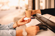 © Cavan Images - Female barista giving coffee to customer while he making payment