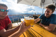 © Cavan Images - Three men toast their beers on restaurant patio
