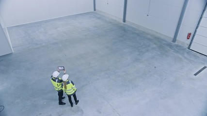 Poster - Industry 4.0 Modern Factory: Two Engineers Use Digital Tablet Computer with Augmented Reality Software Visualizing of Manufacturing Plant Room Mapping. Doing 3D Factory Floor Layout. High Angle Shot