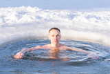 Fototapeta Łazienka - young man swims in an ice hole in cold water in winter, closeup