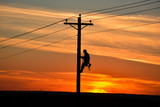 Fototapeta  - Lineman on pole during sunset