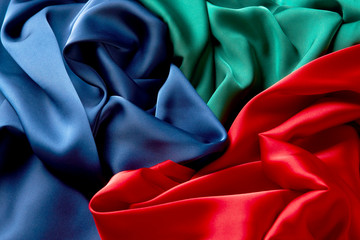 Blue green and red color silk fabric background, top view.