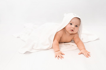 cute baby under a white towel with a hood after a bath. baby in a towel. children's portrait. health