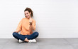 © luismolinero - Young woman with curly hair sitting on the floor inviting to come