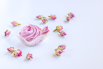 Pink fruit marshmallow and dried buds of roses on the white background. 