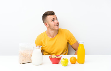 Young blonde man having breakfast laughing and looking up