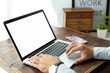 © panitan - mockup image blank screen computer with blank white background for advertising text,hand man using laptop contact business search information on desk at home office.marketing and creative design