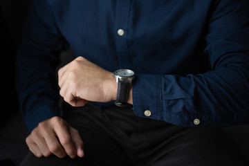 looking at luxury watch on hand check the time.businessman sitting on sofa.concept for managing time organization working,punctuality,appointment.fashionable wearing stylish