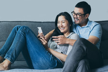 Using Cell Phone Couple Asian Lover Happy Enjoy Sitting On Sofa At Home Looking On Mobile Laugh And Smiling Together Search Information From Internet .concept For Technology Contact Communication