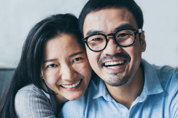 Wall Mural - couple love concept.asian sweet lover man and women smiling taking a selfie sitting on sofa at home on anniversary hug in embrance each other.photo of people smile enjoy  Beautiful romantic time