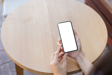 Mockup image blank white screen cell phone.man hand holding texting using mobile on desk at outdoor cafe.background empty space for advertise text.people contact marketing business,technology