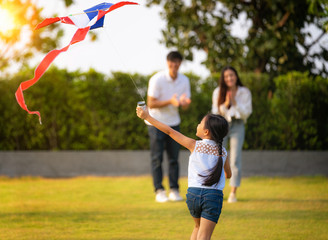 Wall Mural - Happy family  launch a kite on nature at sunset