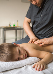 Wall Mural - Boy toddler relaxes from a therapeutic massage. Physiotherapist working with patient in clinic to the back of a child