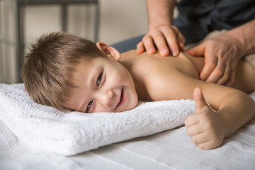 Wall Mural - Boy toddler relaxes from a therapeutic massage. Physiotherapist working with patient in clinic to the back of a child