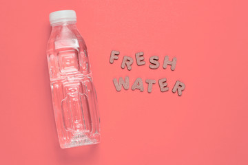 Wall Mural - Bottled water on pink background with the words fresh water.