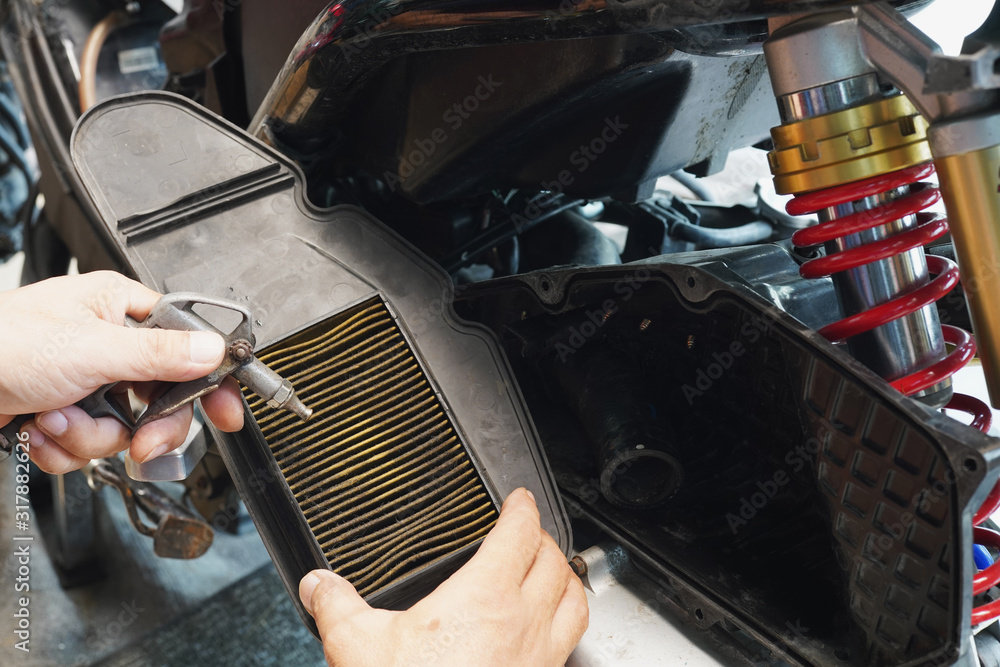 photo-stock-mechanic-holding-dirty-engine-air-filter-over-big-scooter