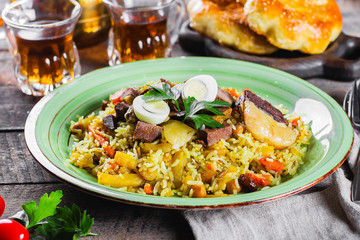 Wall Mural - National Traditional Uzbek pilaf with meat and rice on a wooden table. Oriental cuisine concept. Close-up image