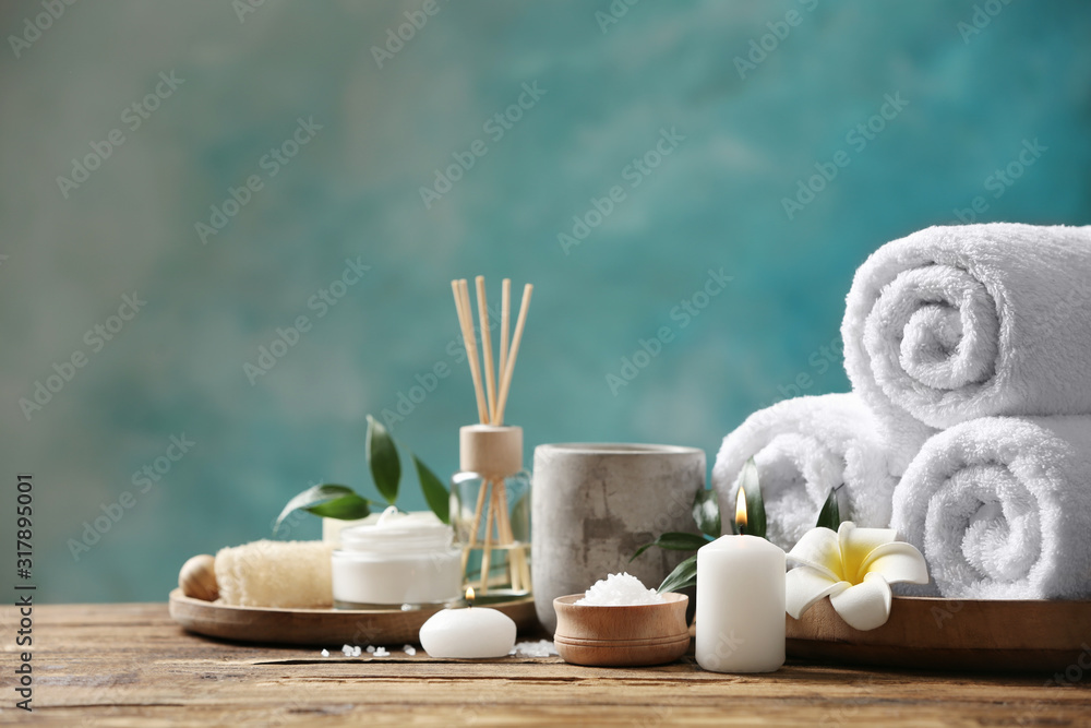 Beautiful spa composition with towels on wooden table against light blue background - obrazy, fototapety, plakaty 