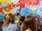 Fototapeta Młodzieżowe - young people draw graffiti on the wall of the building