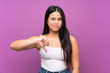 © luismolinero - Young teenager Asian girl over isolated purple background showing thumb down sign
